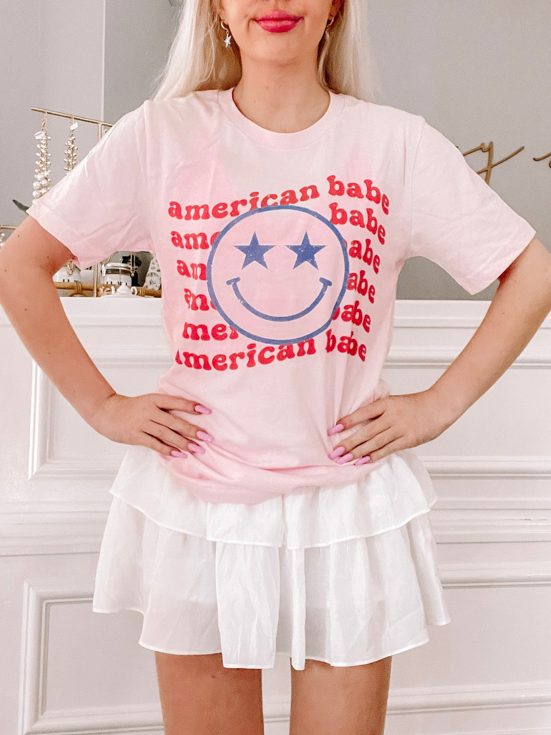 Pink tie-dye tee with a retro smiley face graphic paired with a white ruffle skirt.
