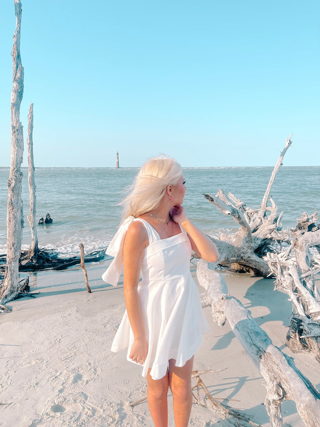 White sundress on a sunny beach, near driftwood and ocean. Girls Who Twirl Dress from Sassy Shortcake
