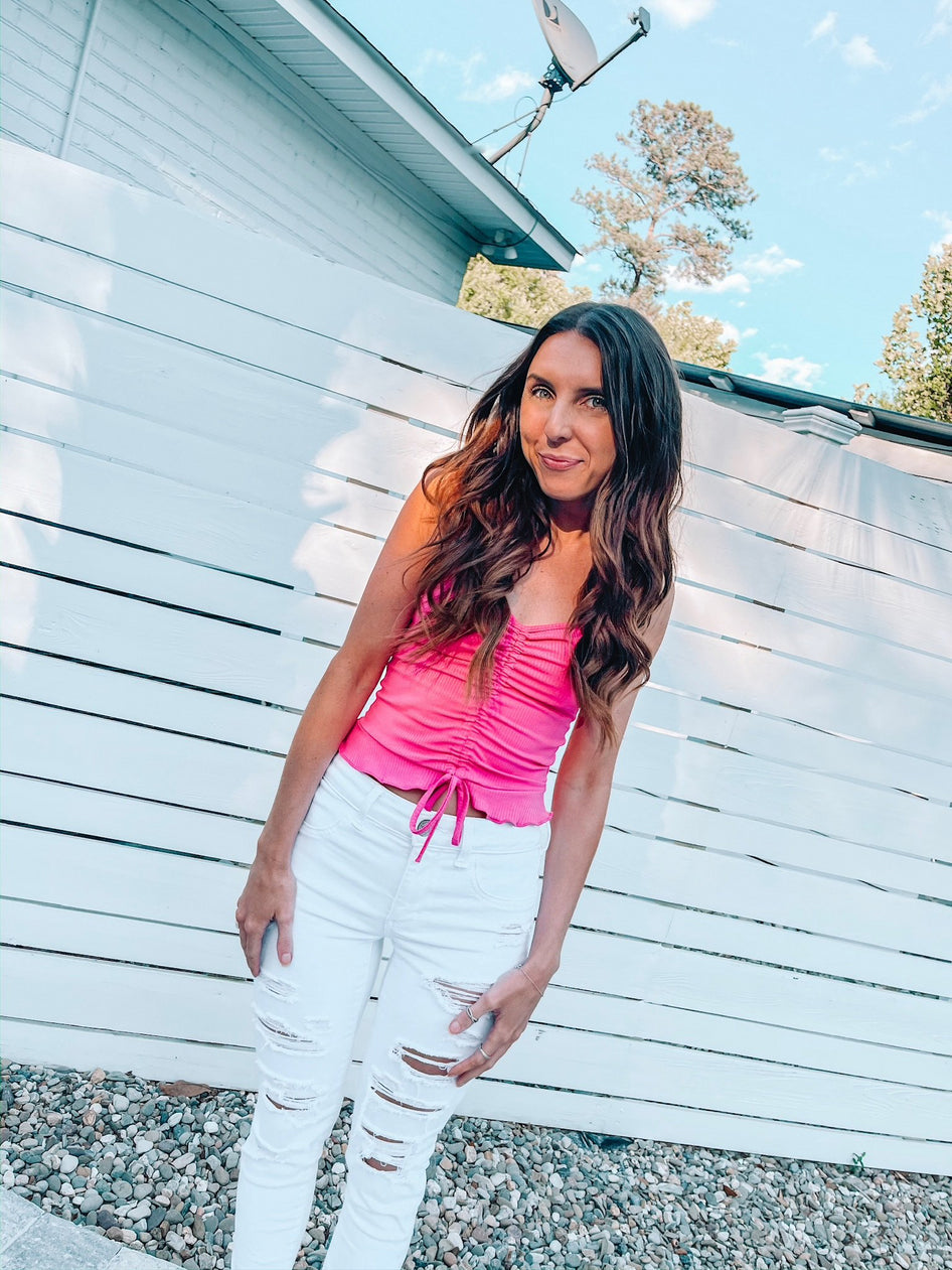 Hot pink ruched crop top, the Haute to Trot Top,  worn with white distressed jeans.

