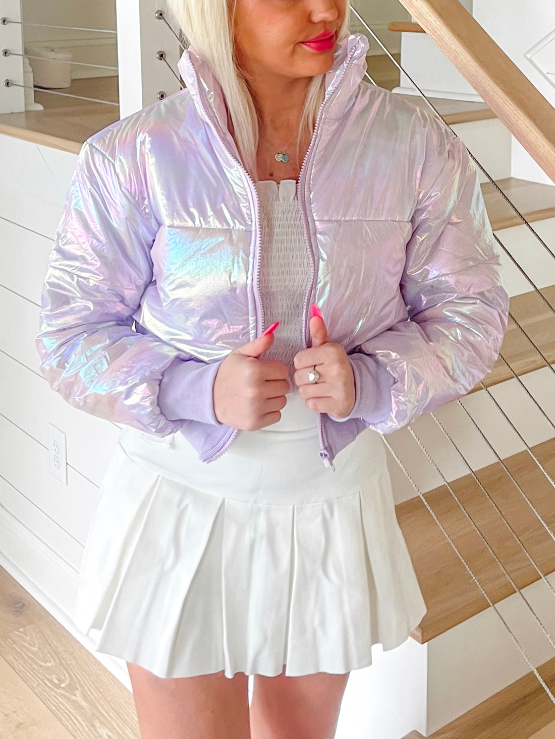 Lilac iridescent puffer jacket, cropped style, modeled indoors near staircase.
