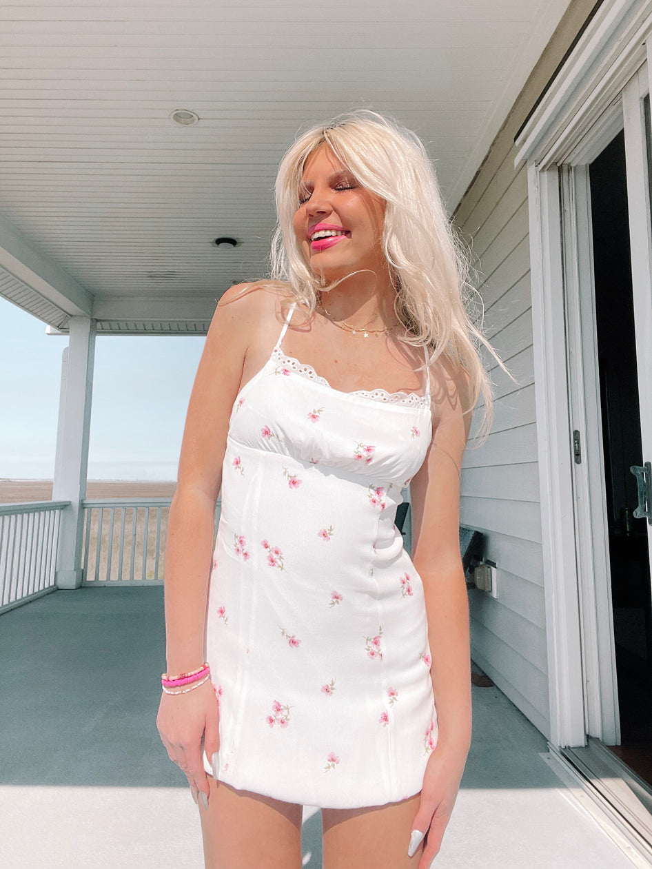 White floral mini dress on a sunny porch.

