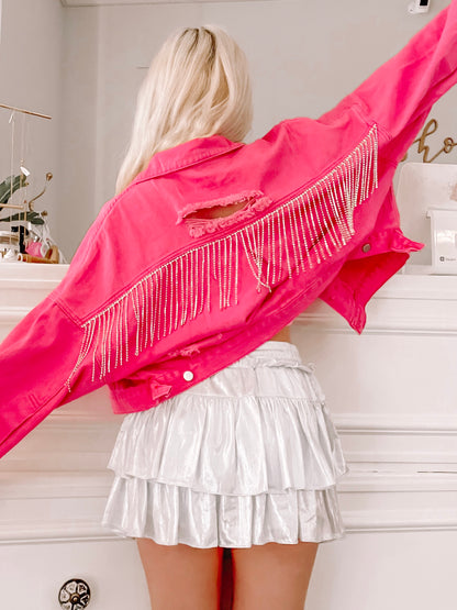Hot pink denim jacket with distressed detailing and rhinestone fringe, shown from the back.
