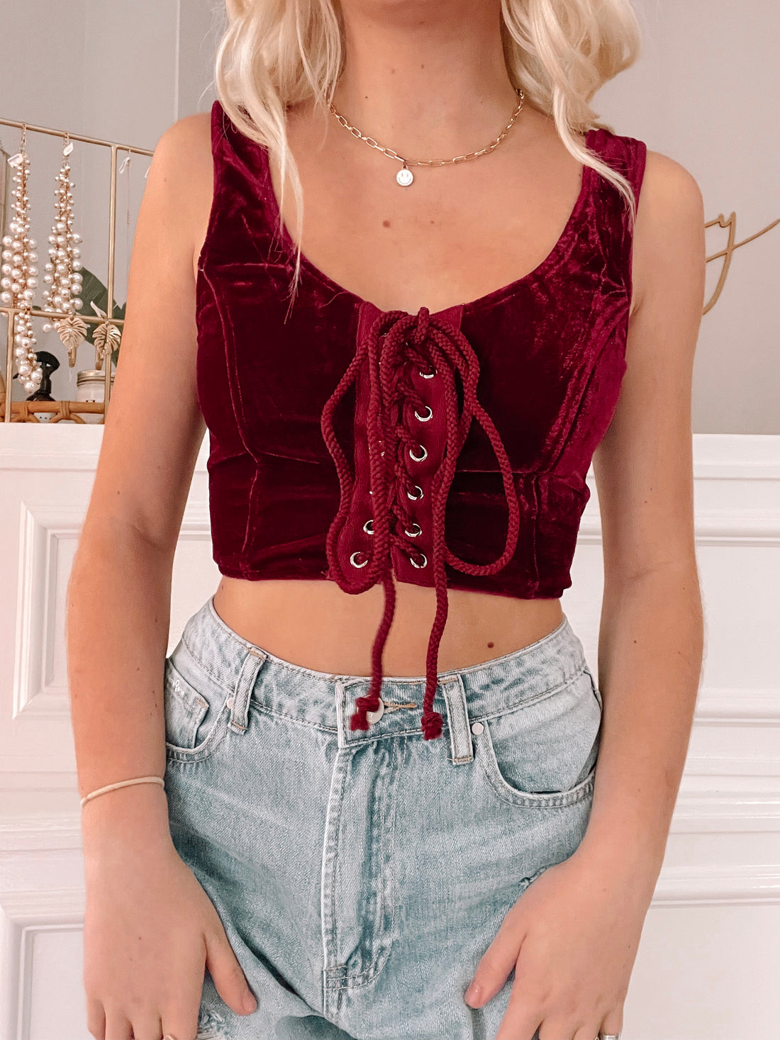 Crimson velvet corset top with lace-up front, styled with light wash denim.
