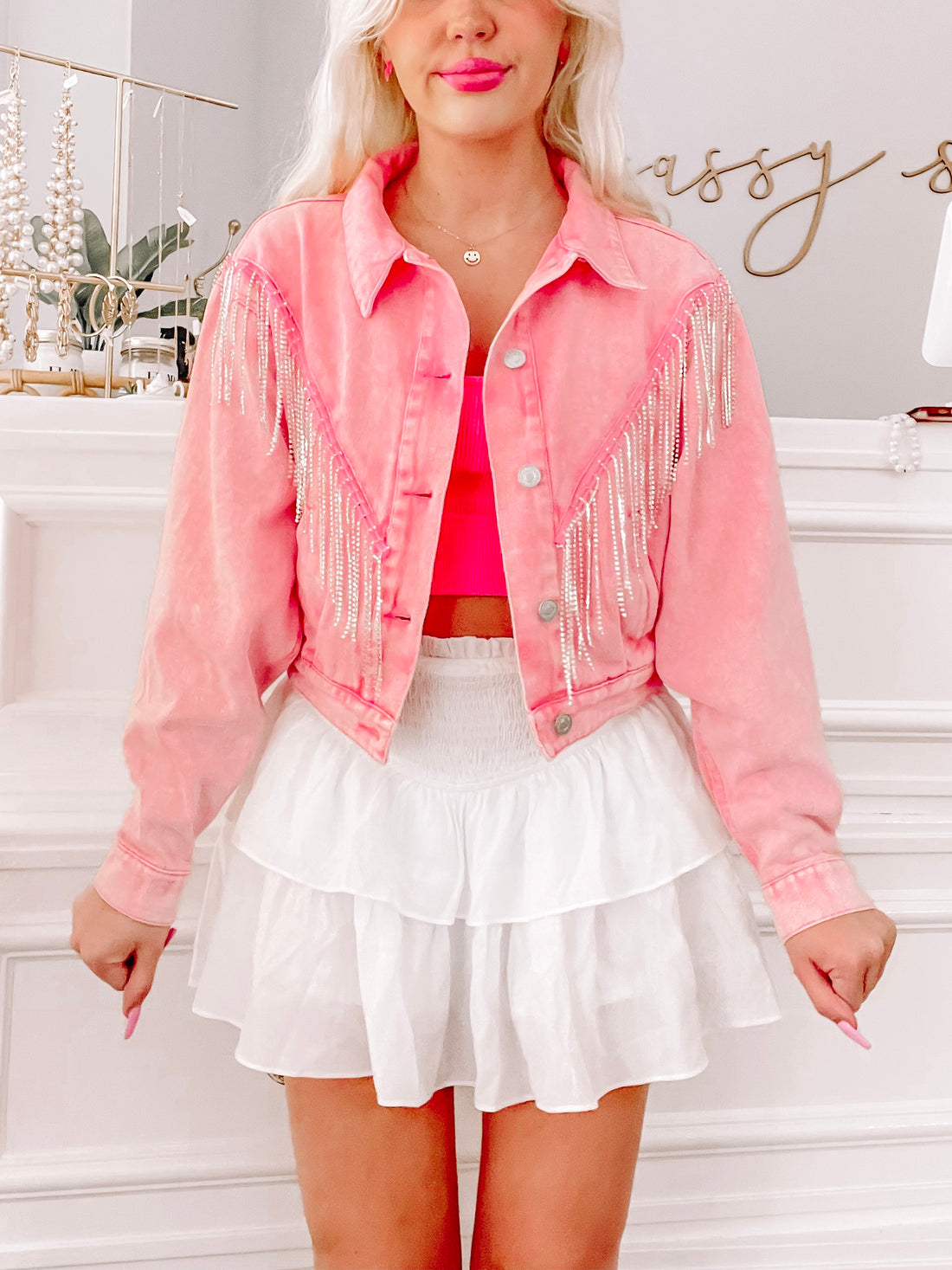 Pink denim jacket with rhinestone fringe, modeled with white tiered mini skirt.
