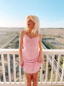 Pink gingham mini dress on a deck overlooking marshland.
