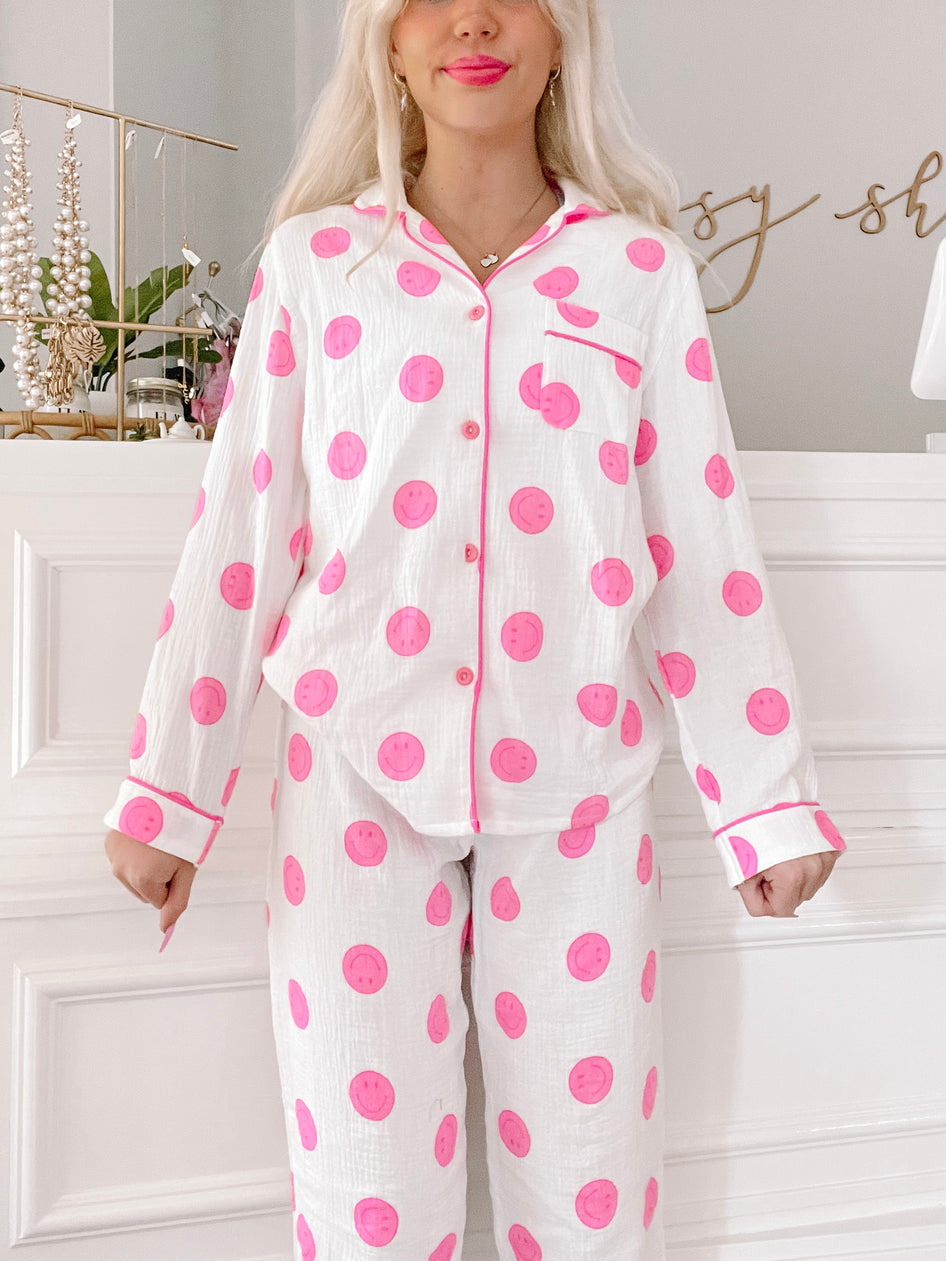 Pink smiley face pajama set; long sleeves, button-up top, and matching pants.
