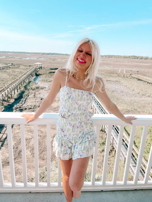 Floral print two-piece summer outfit: white crop top and ruffled shorts.
