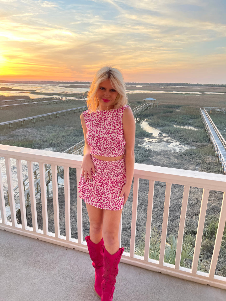 Woman wearing pink floral print Wild About You Set two-piece outfit and pink boots.
