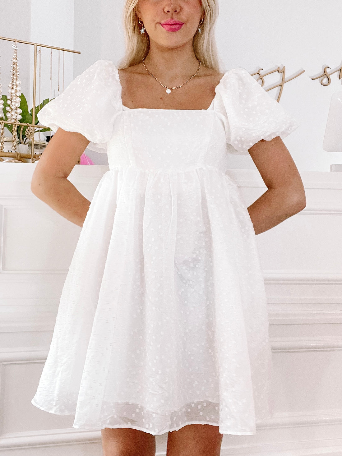 White eyelet mini dress with puff sleeves, shown on model against white background.
