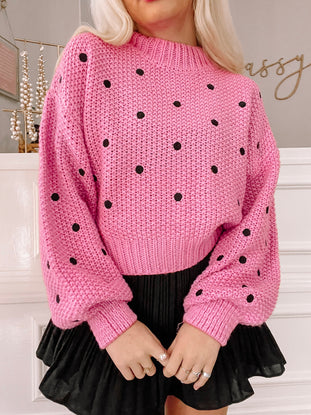 Pink Tilly Dot sweater with black polka dots, balloon sleeves, and cropped length.
