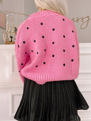 Pink knit sweater with black polka dots, shown from the back.

