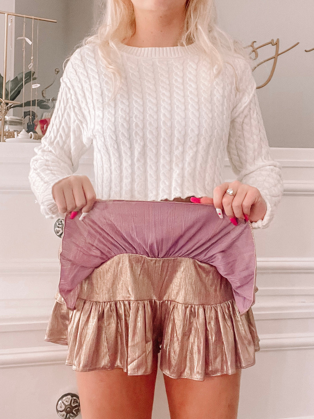 Rose gold metallic mini skirt with ruffled hem and lilac lining, shown on a model.
