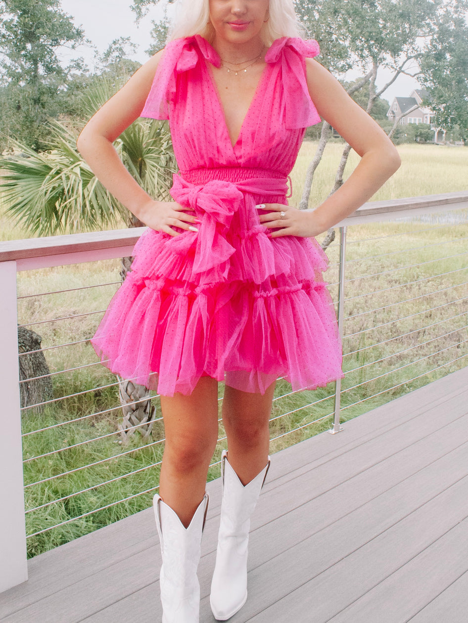 Hot pink tulle mini dress with tiered ruffles, worn outdoors on a deck.
