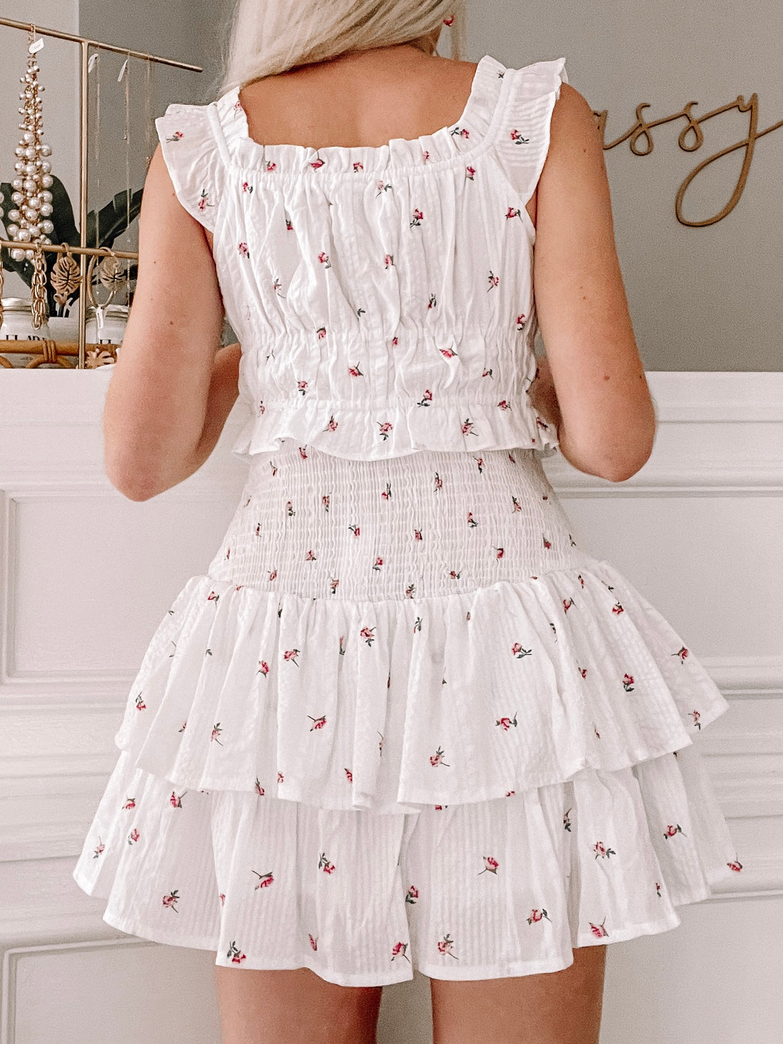 White floral two-piece outfit; smocked bodice and tiered ruffle skirt.

