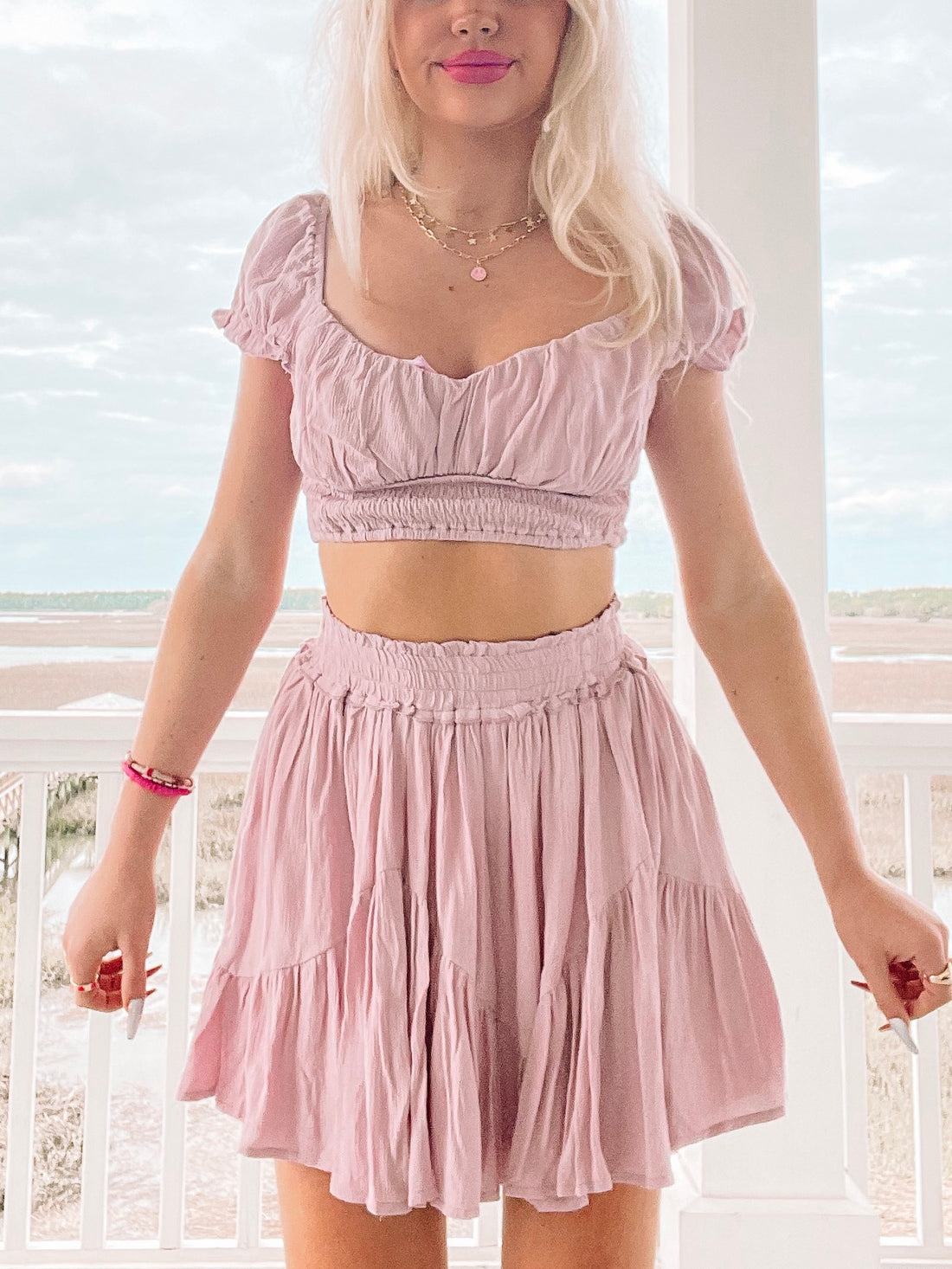 Lilac two-piece outfit:  cropped top and tiered mini skirt, worn outdoors near water.
