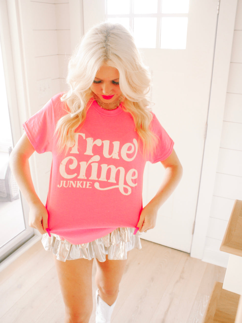 Pink 'True Crime Junkie' tee shirt model shot; bright, casual style.
