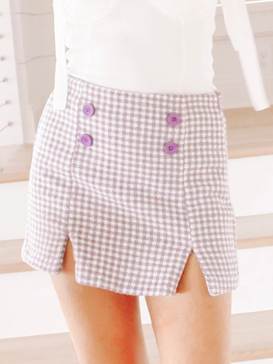 Purple houndstooth mini skort with side slits and purple buttons.
