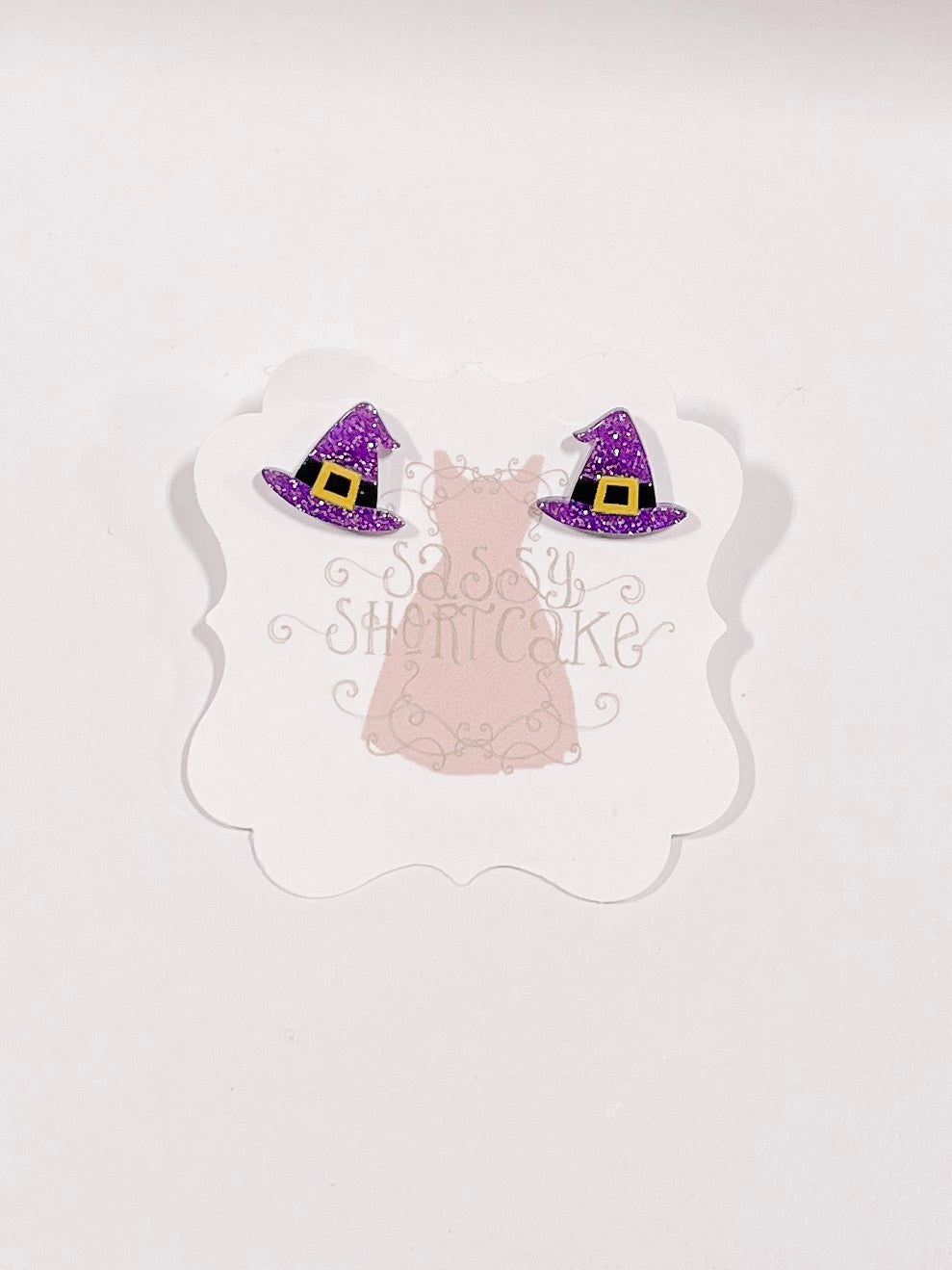 Purple glitter witch hat earrings displayed on a card.
