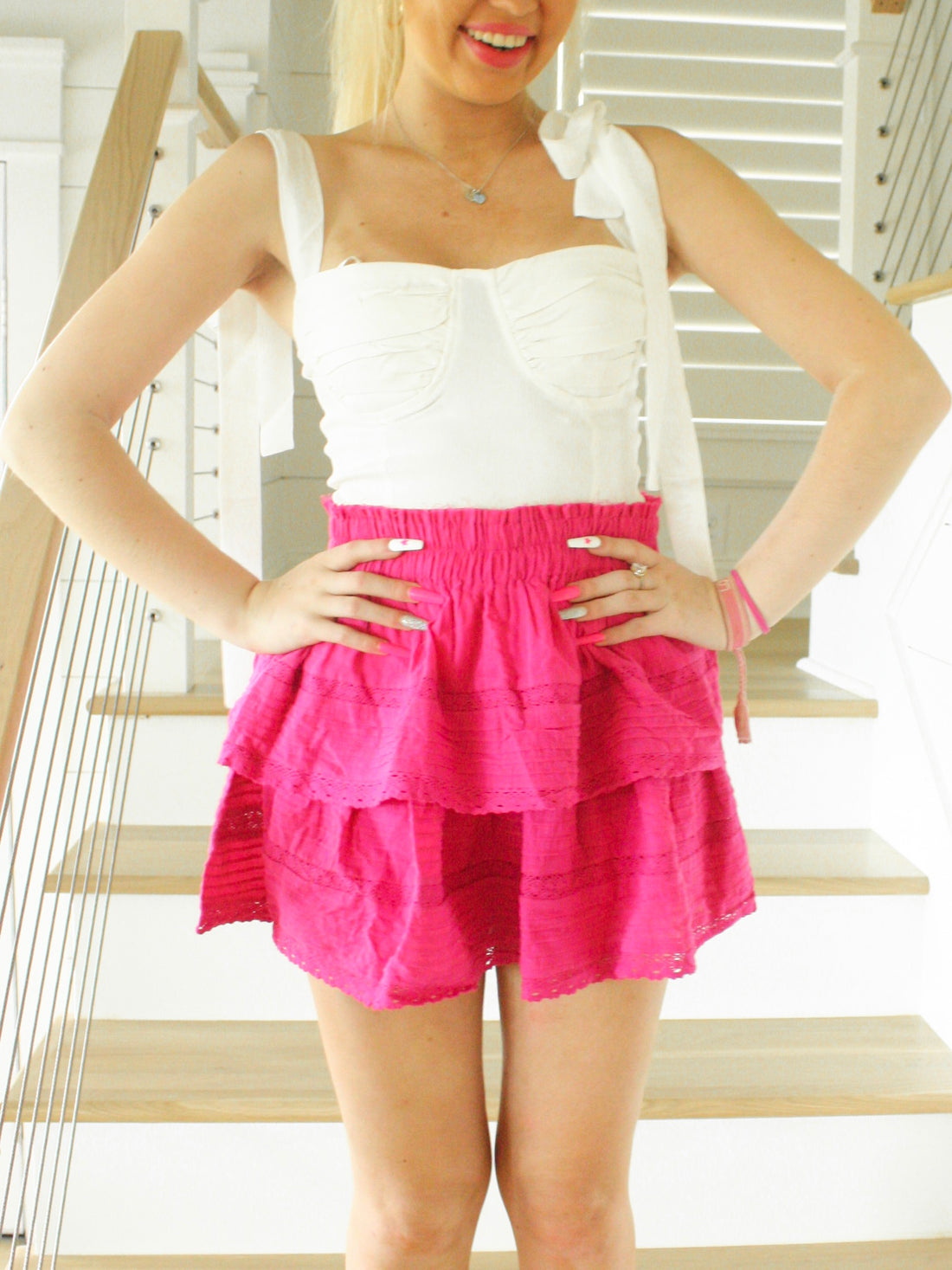 Hot pink tiered mini skirt, layered fabric with lace trim, worn indoors on a staircase.
