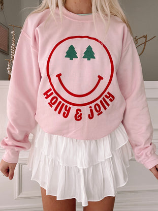 Pink Holly Jolly sweatshirt with Christmas tree smiley face design
