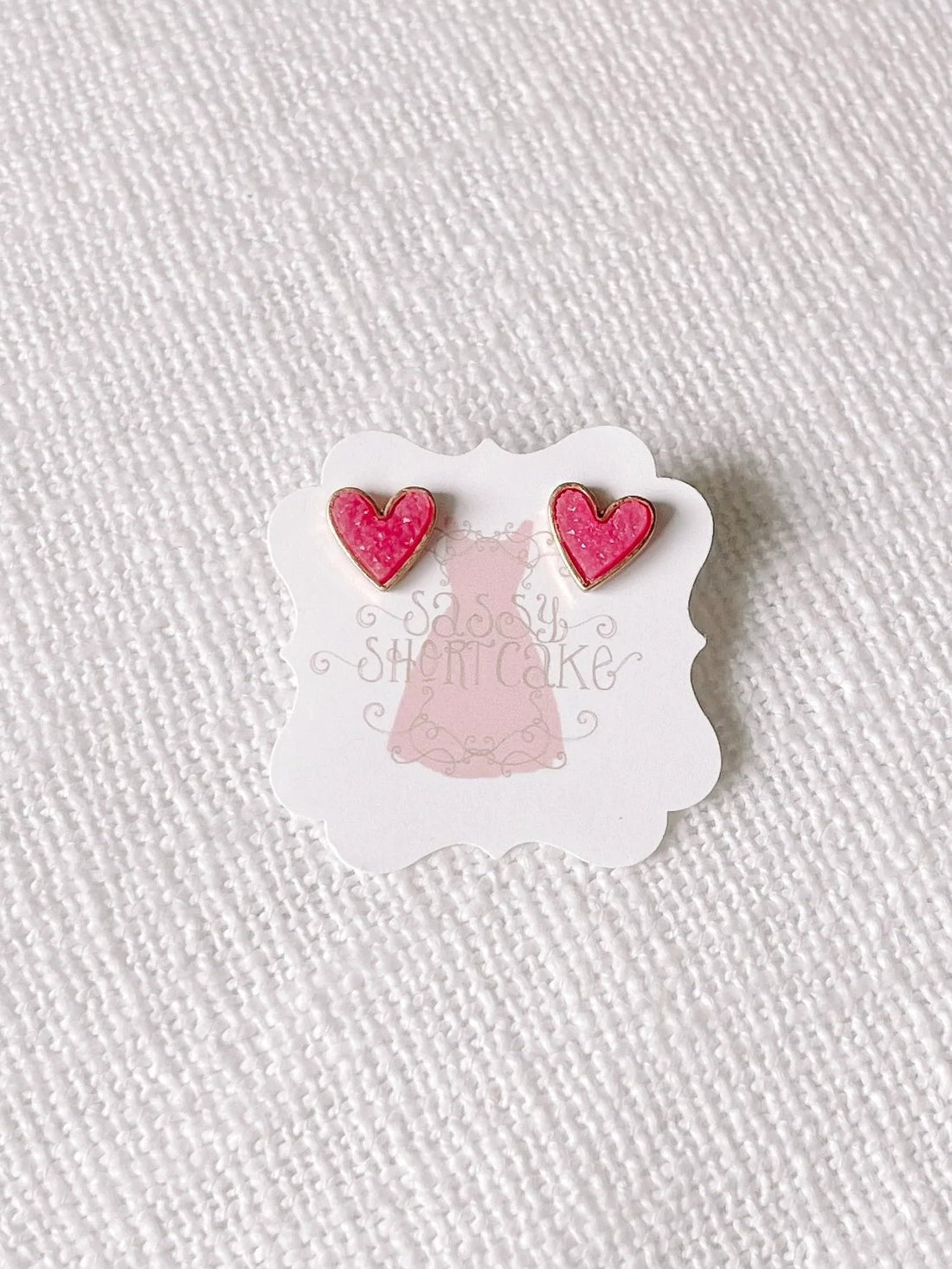 Pink glitter heart stud earrings with gold accents
