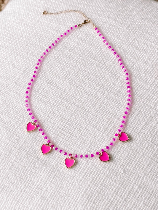 Pink and white beaded necklace with pink heart charms.