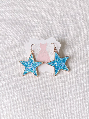 Blue Chasing Stars glitter star earrings with gold hoops.
