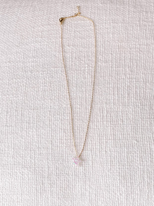 Gold chain necklace featuring a sparkly, pastel pink star charm, displayed on a white textured background.
