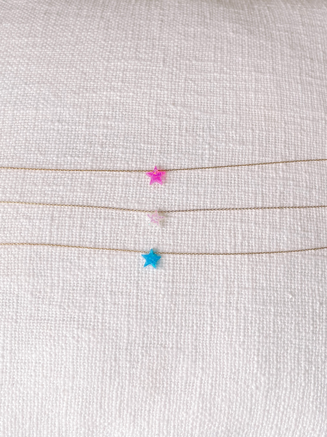 Gold chain necklace featuring pink, white, and blue star opal pendants.
