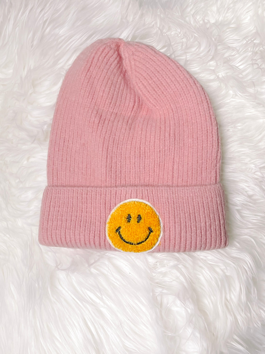 Light pink knit beanie with yellow smiley face patch
