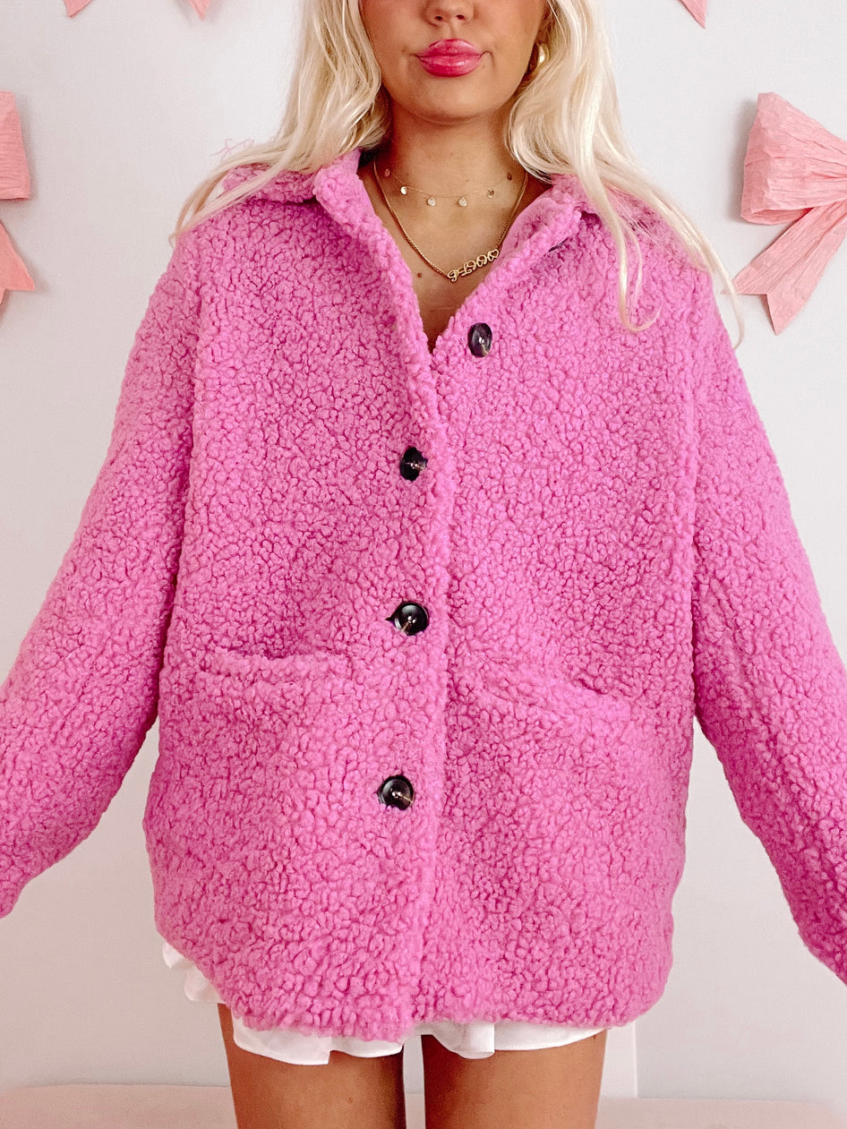 Pink sherpa shacket with button closure, shown on model against a light background.
