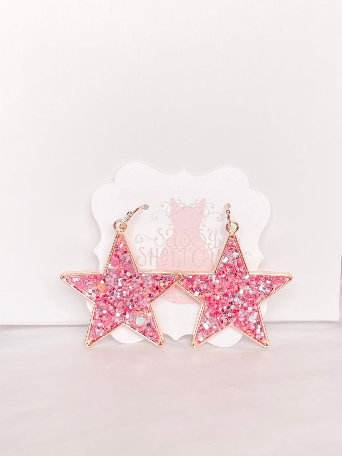 Pink glitter star earrings with gold accents; Chasing Stars design.
