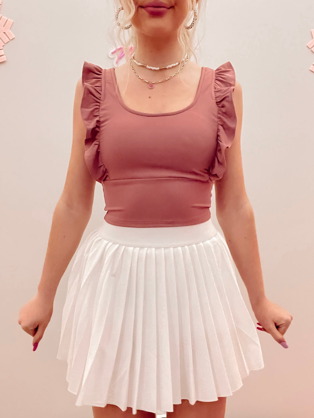 Dusty rose ruffle-trimmed crop top paired with a white pleated mini skirt.
