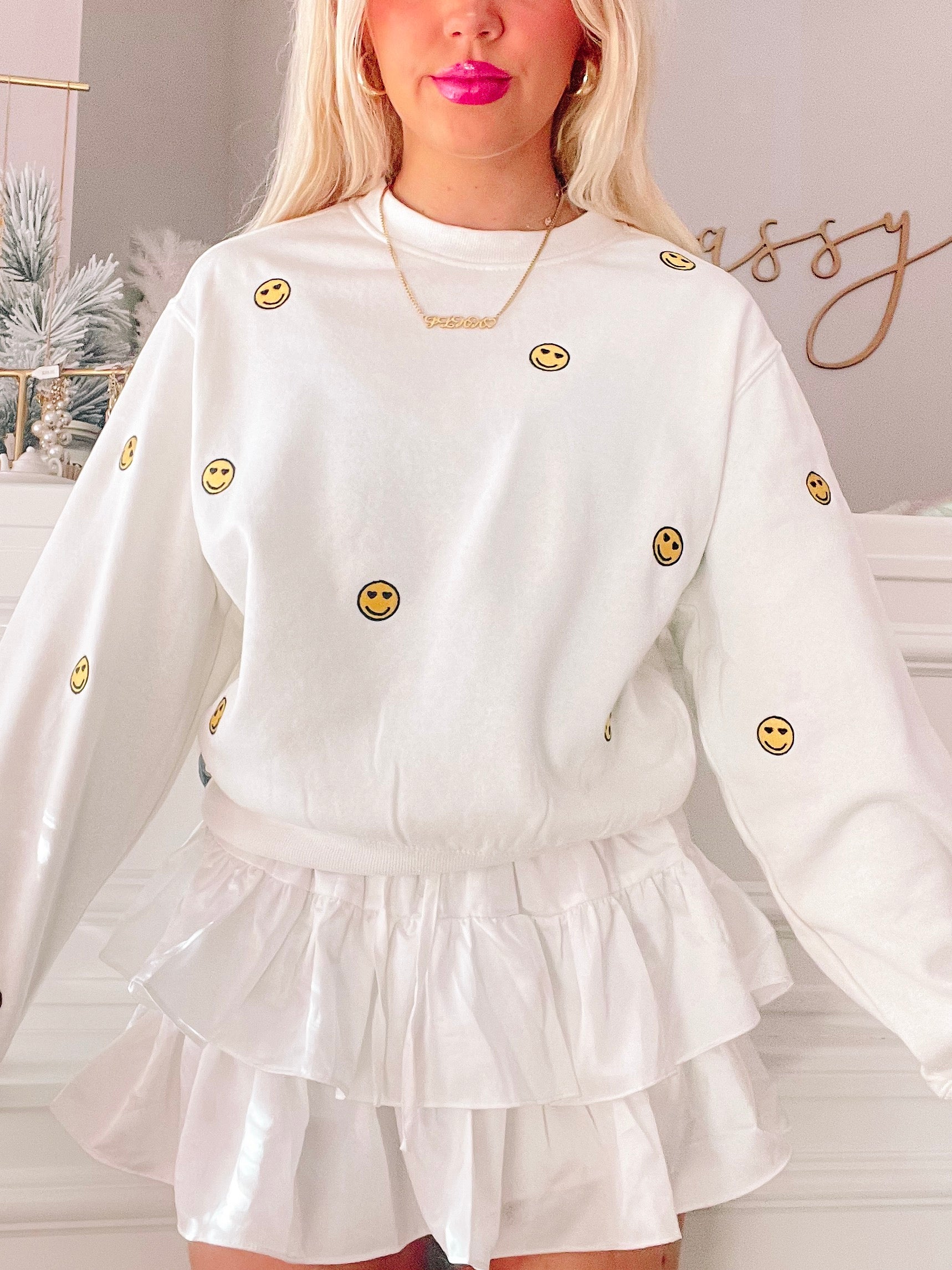 White Happy Hearts crewneck sweatshirt with embroidered smiley faces.
