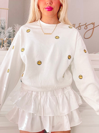 White Happy Hearts crewneck sweatshirt with embroidered smiley faces.
