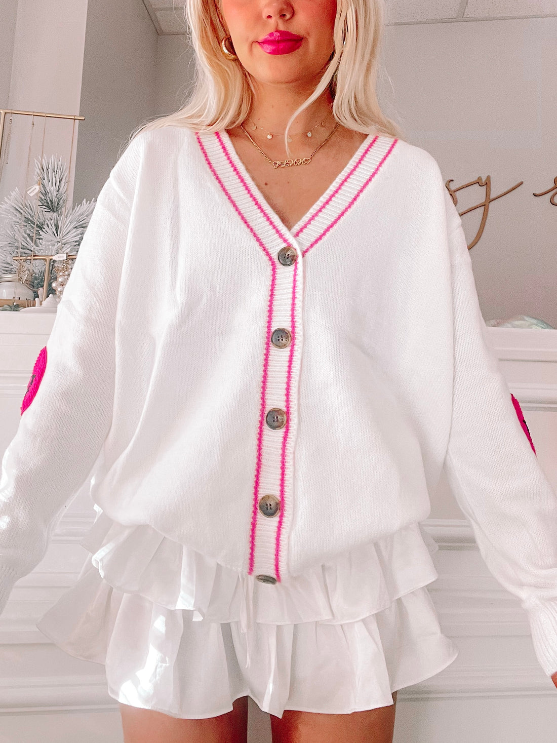 White Styles of Smiles cardigan with pink trim and embroidered hearts, button front.
