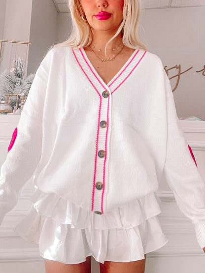 White Styles of Smiles cardigan with pink trim and embroidered hearts, button front.
