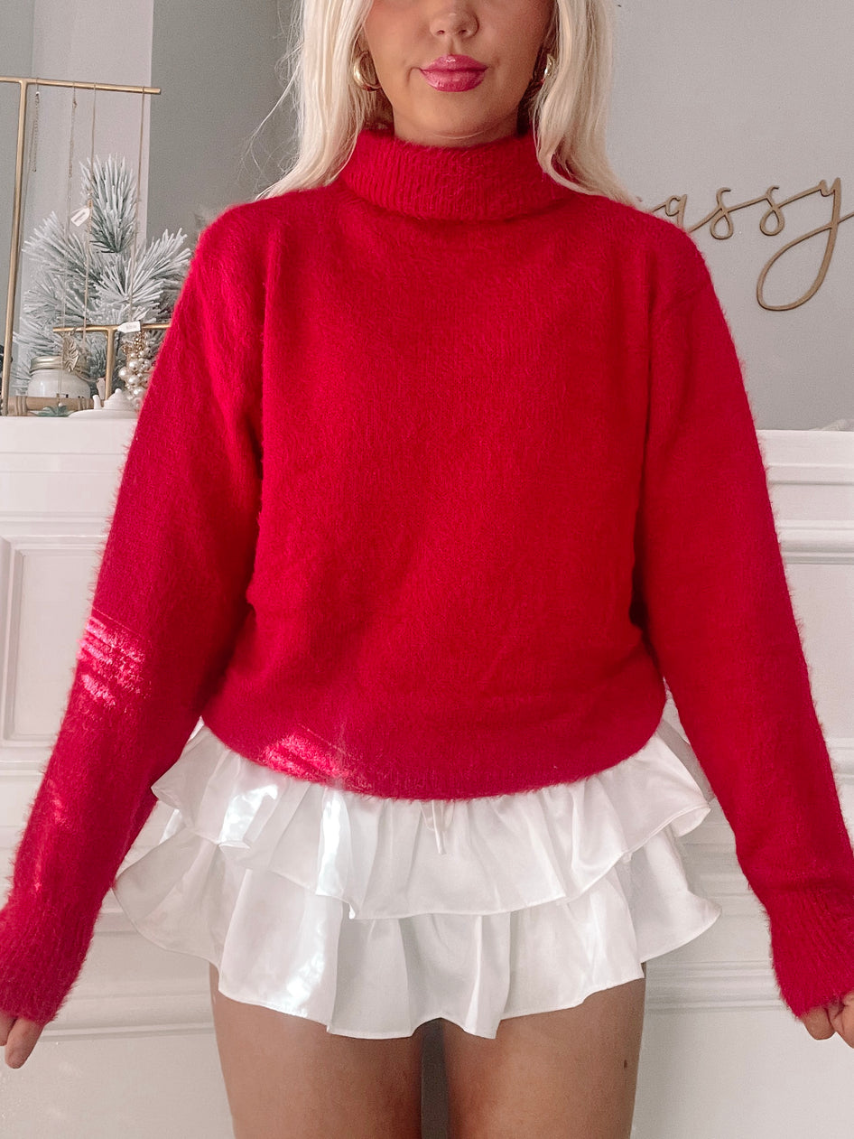 Fuzzy red turtleneck sweater styled with a white ruffled skirt.
