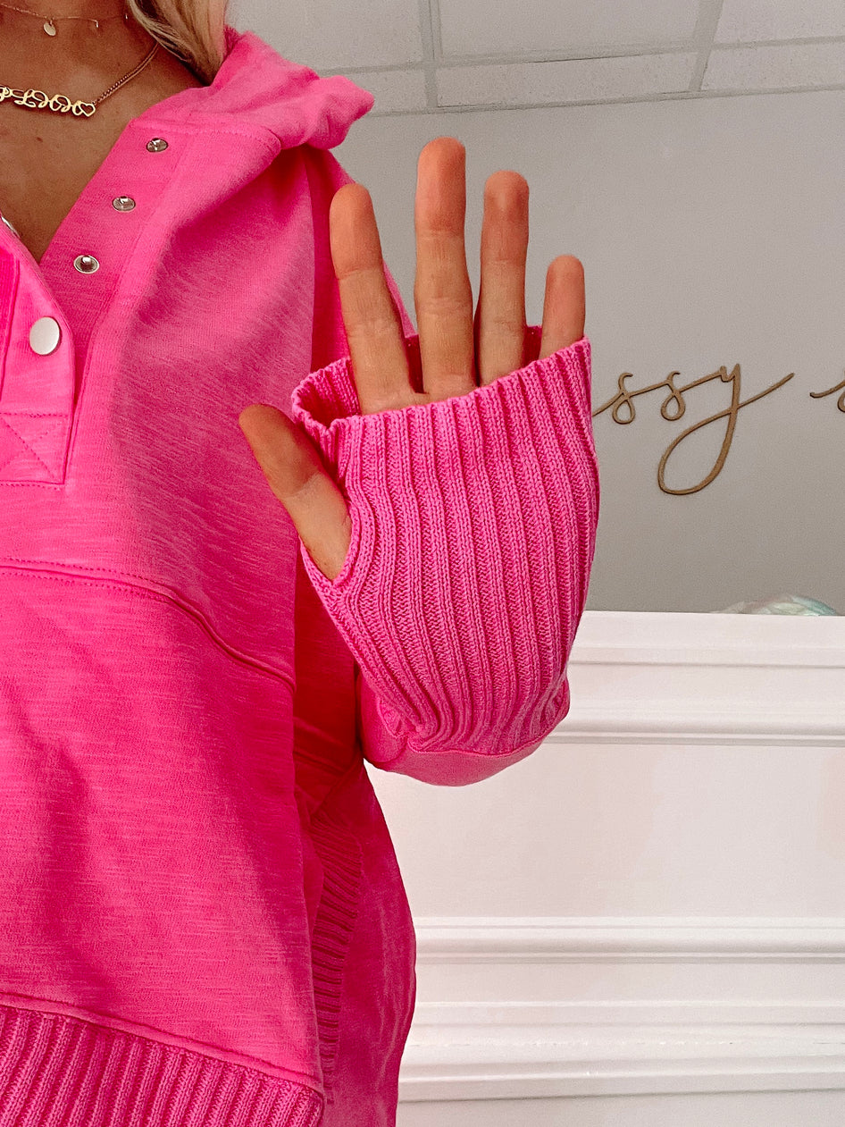 Close-up of vibrant pink sweater sleeve, ribbed knit detail, showcasing soft texture.
