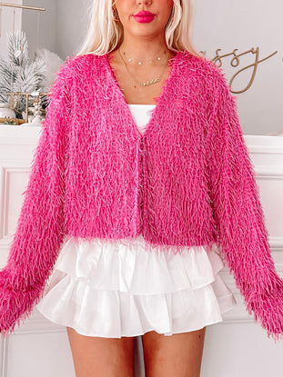 Hot pink fluffy cardigan styled with a white ruffle skirt.
