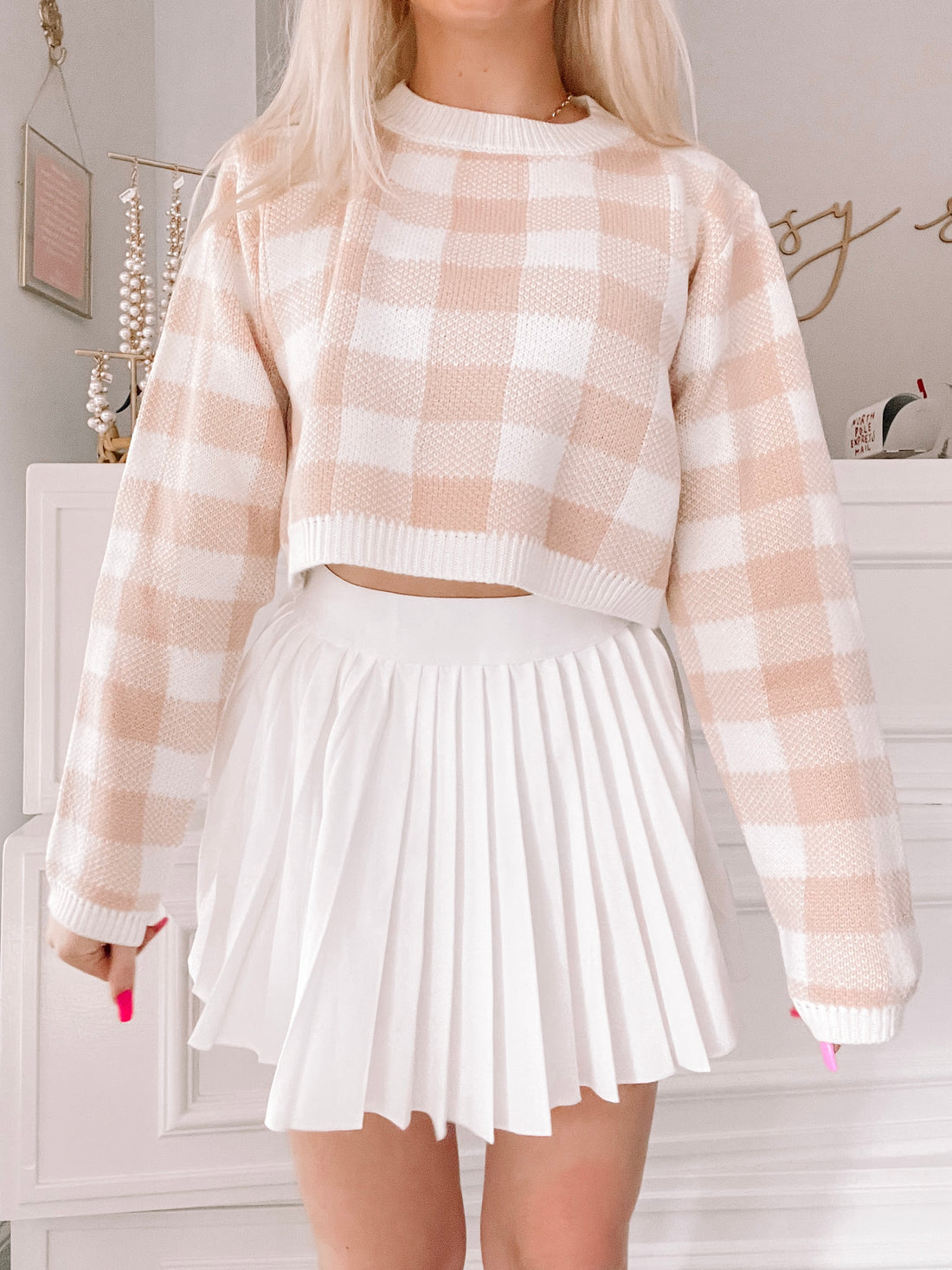 Blush pink and white gingham cropped sweater paired with a white pleated skirt.
