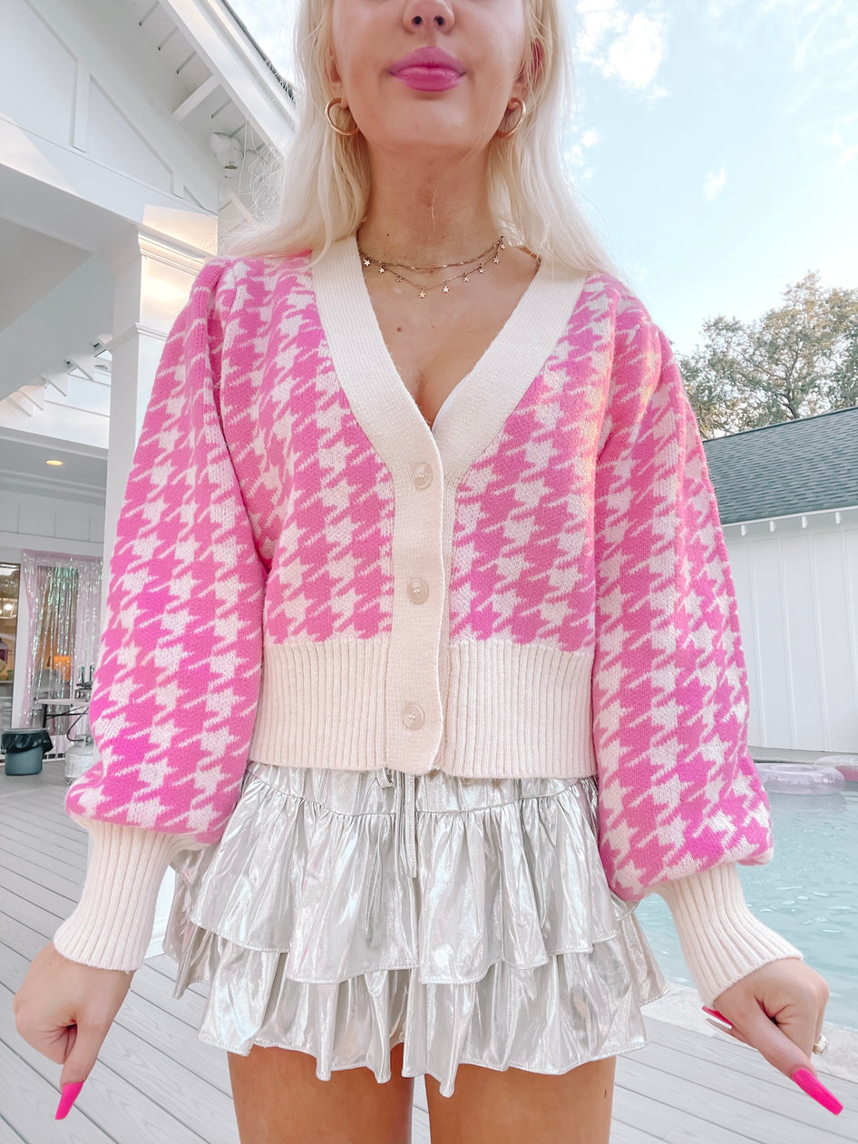 Pink houndstooth cardigan with cream trim, modeled outdoors.
