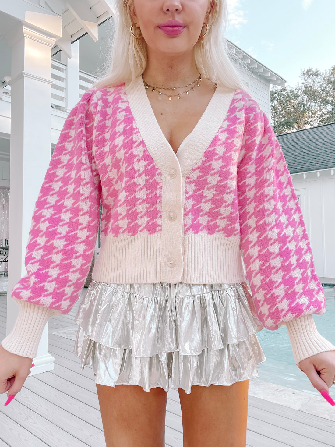 Pink houndstooth knit cardigan with cream trim, button front, and puffy sleeves, modeled outdoors.
