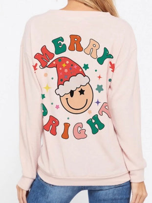 Pink Christmas sweatshirt featuring a whimsical smiley face design and "Merry Bright" text.
