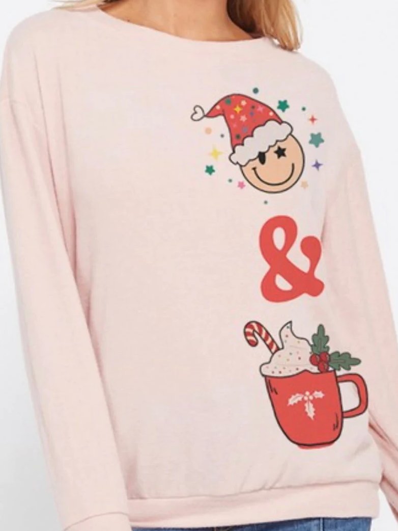 Pink Christmas sweater featuring a festive smiley face and hot cocoa graphic.
