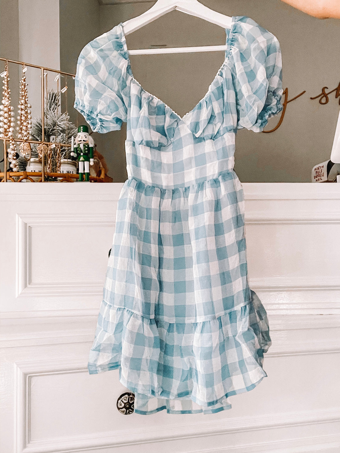 Light blue gingham mini dress with puff sleeves, hanging on a white hanger.
