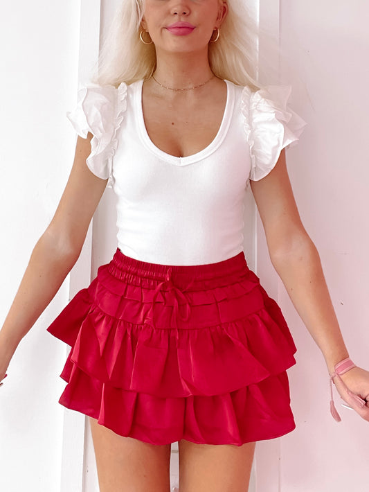 Crimson ruffled mini skirt layered for a flirty look.