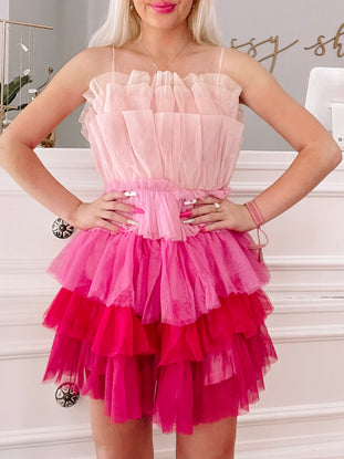 Pink tulle mini dress with layered ruffles, ombre effect transitioning from light pink to fuchsia.
