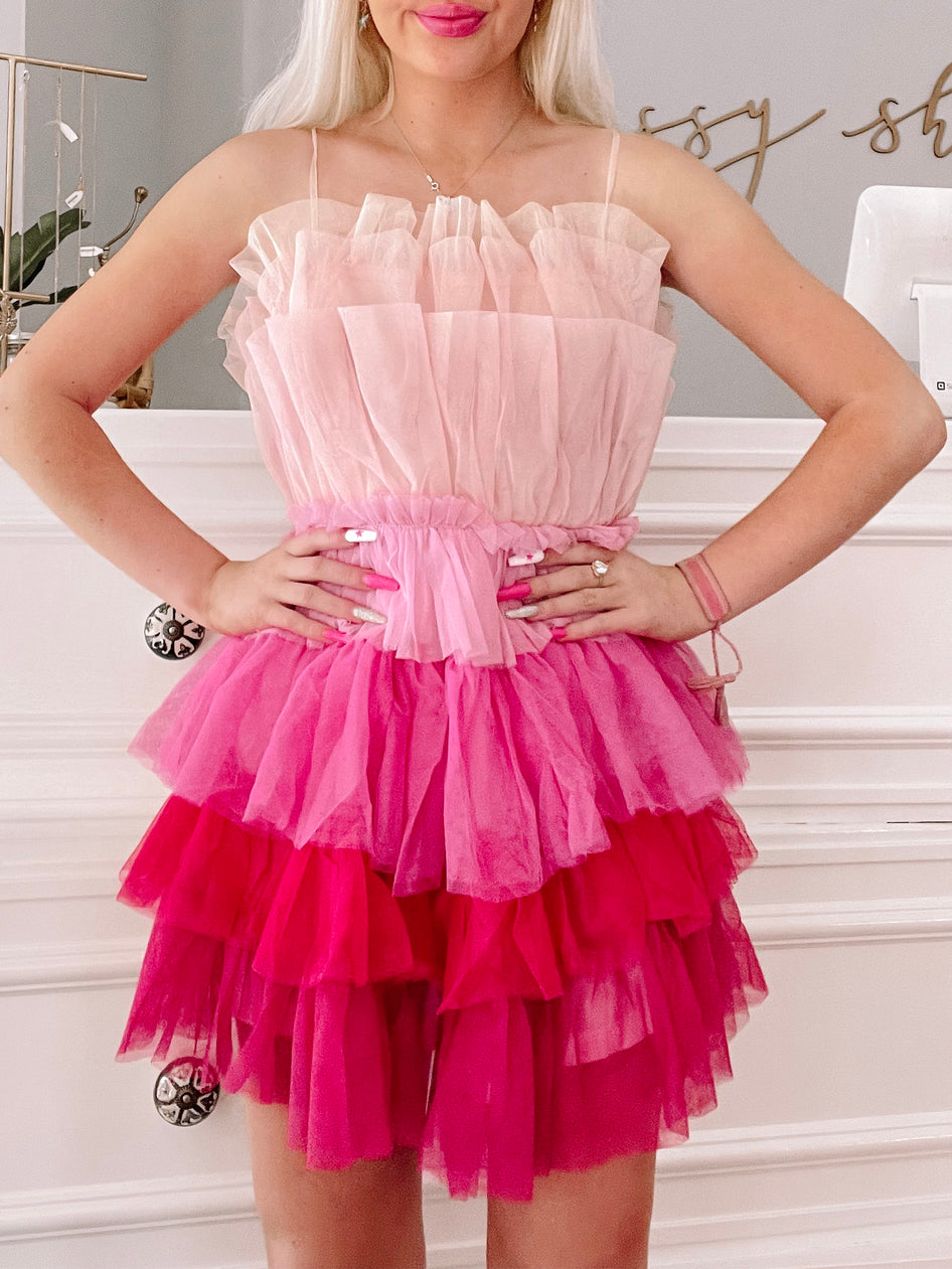 Pink tulle mini dress with layered ruffles, ombre effect transitioning from light pink to fuchsia.
