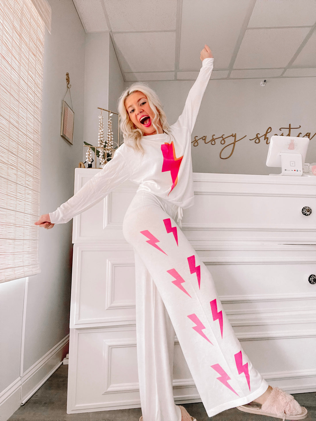 White pajama set with pink lightning bolt print, styled in a bright interior.
